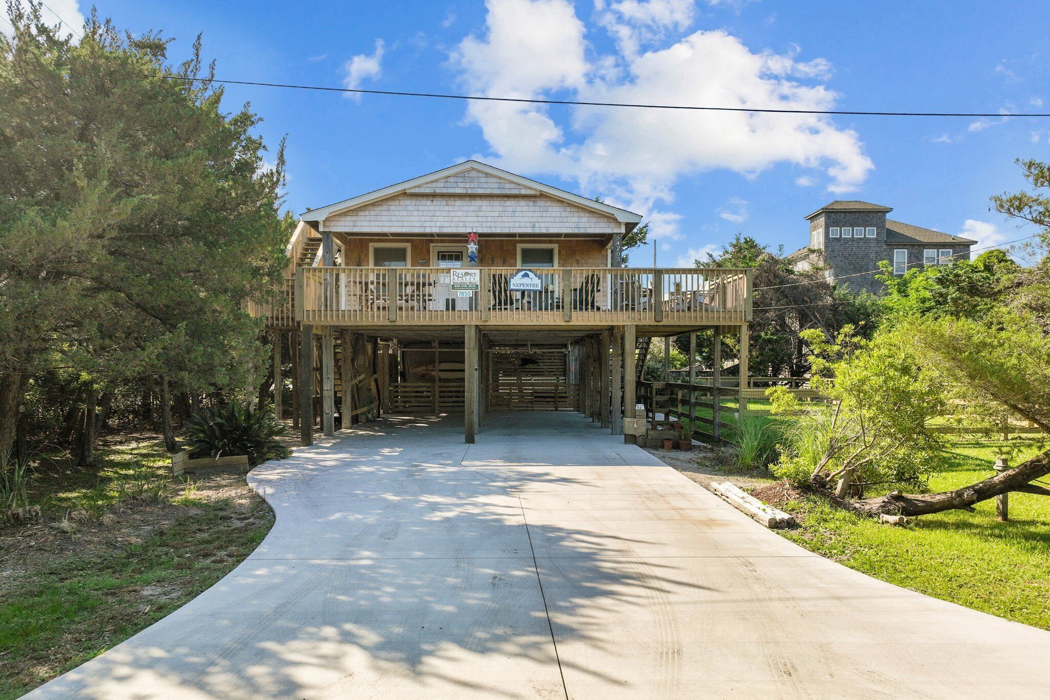 A two-story house with a balcony, a driveway leading to the entrance, and a small garden area.