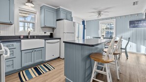 Una cocina moderna con armarios azules, un refrigerador blanco y una barra con taburetes.