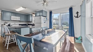 Cocina con isla central, electrodomésticos blancos y muebles azules.