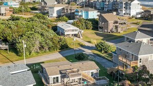 Zona residencial costera con casas, una terraza de madera y vista despejada al océano.