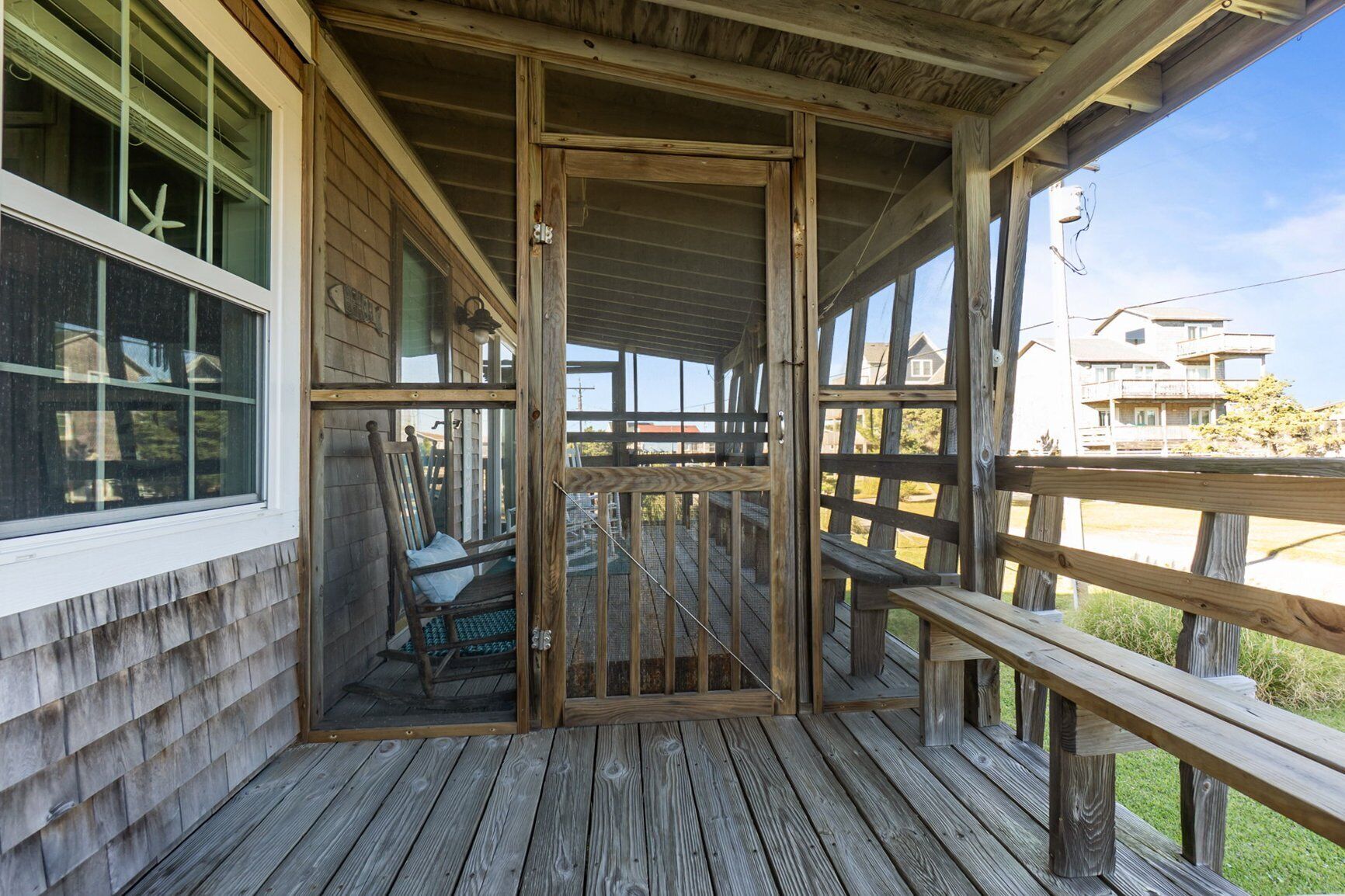 A wooden deck with a covered porch, a chair, and a railing.