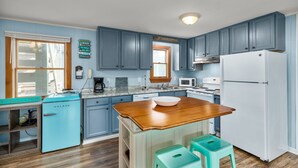 Eine Küche mit blauen Schränken, einer Holz Arbeitsplatte, einem weißen Kühlschrank und einem Spülbecken.