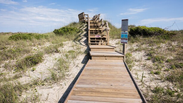 A wooden boardwalk leading up a sandy dune with a sign indicating 'KEEP OFF THE DUNES'. - 7950- Ocean, | Coastal Hatteras Escape | Walk to Beach (Hatteras)