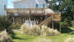 A two-story house with a wooden deck and a staircase leading to a covered porch. - 7950- Ocean, | Coastal Hatteras Escape | Walk to Beach (Hatteras)
