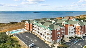 Et kysthotel med flere bygninger, parkeringsplads og havudsigt.