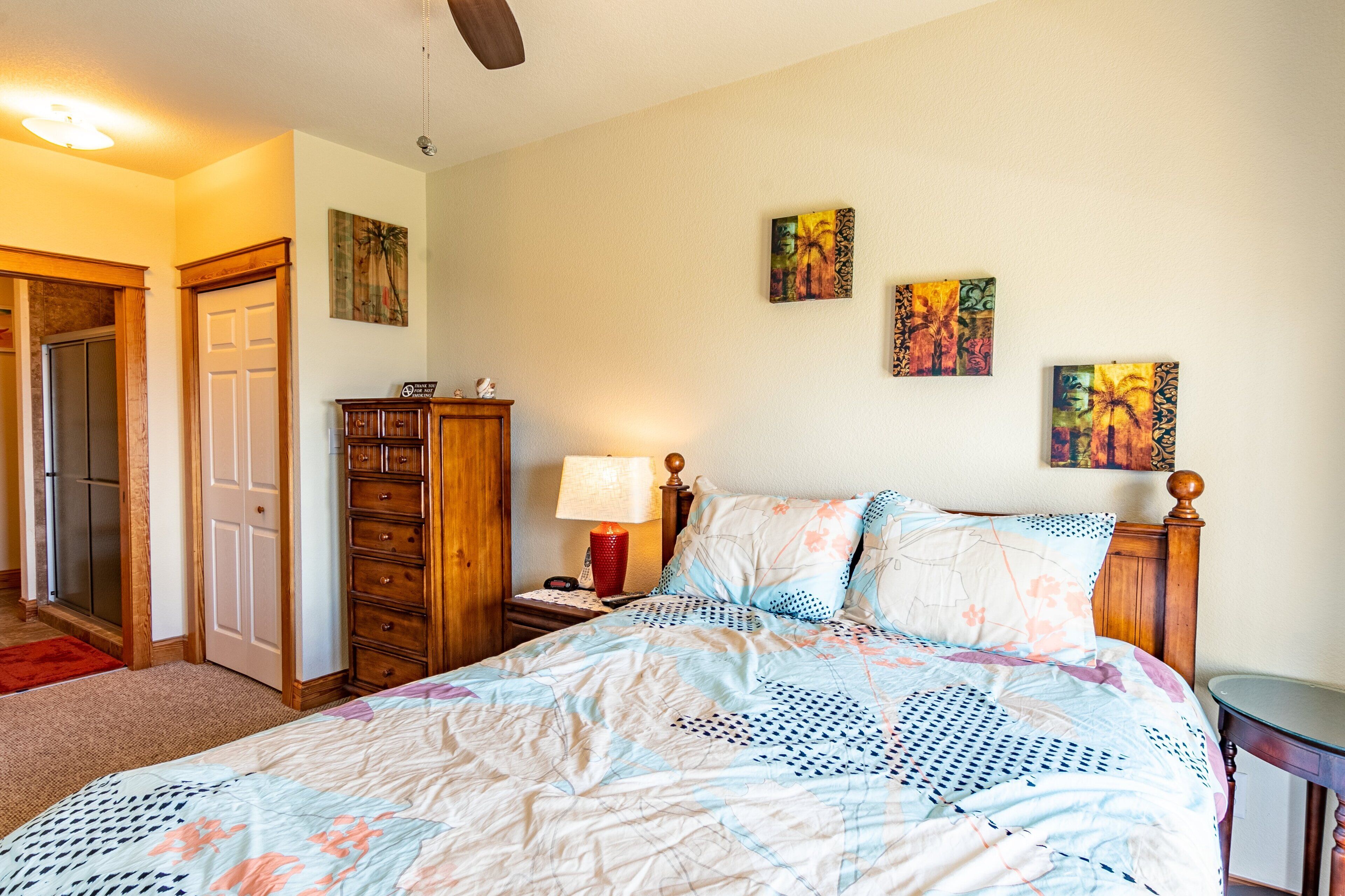 Un dormitorio con cama, cómoda de madera y una obra de arte en la pared.