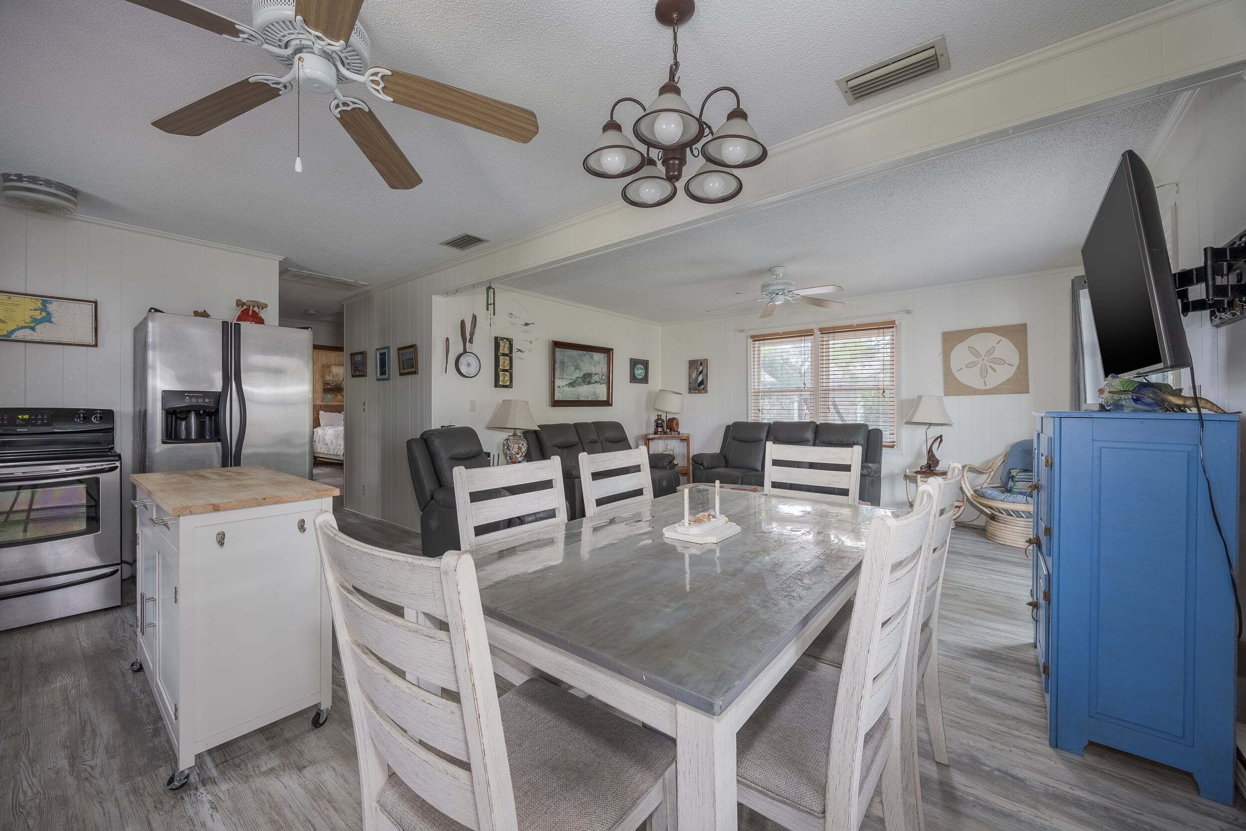 A dining area with a table and chairs, a ceiling fan, and a kitchen with appliances.