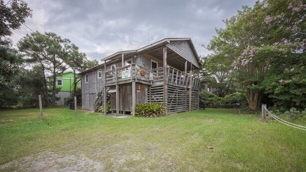 A rustic wooden house with a porch and a fenced yard. - 7602- Drydock, Dog-Friendly Avon Cottage Near the Beach (Avon)