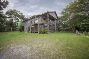 A rustic wooden house with a porch, surrounded by a grassy yard and trees. - 7602- Drydock, Dog-Friendly Avon Cottage Near the Beach (Avon)