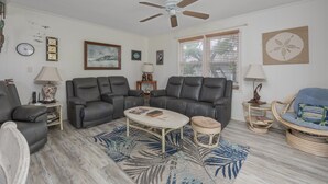 A living room with a ceiling fan, a sofa set, a coffee table, and a wicker chair. - 7602- Drydock, Dog-Friendly Avon Cottage Near the Beach (Avon)