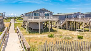 A beachfront property with wooden walkways leading to elevated houses with balconies. - 7913-Southern Comfort - Hatteras Oceanfront Escape | Dog Friendly (Hatteras)