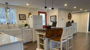 A modern kitchen with white cabinetry, a wooden island, and pendant lighting. - Cottage in Edgecomb - Waterfront Holiday Getaway (Edgecomb)