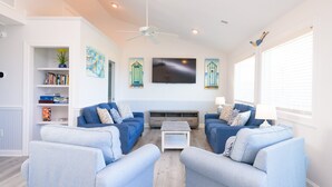 Una sala de estar con dos sofás azules, una mesa de centro blanca y un televisor de pantalla plana en la pared.