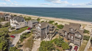 A coastal residential area with houses, a beach, and a clear view of the ocean. - 7700-Lee's Landing - Oceanfront Avon | Pool & Hot Tub | Sleeps 10 (Avon)