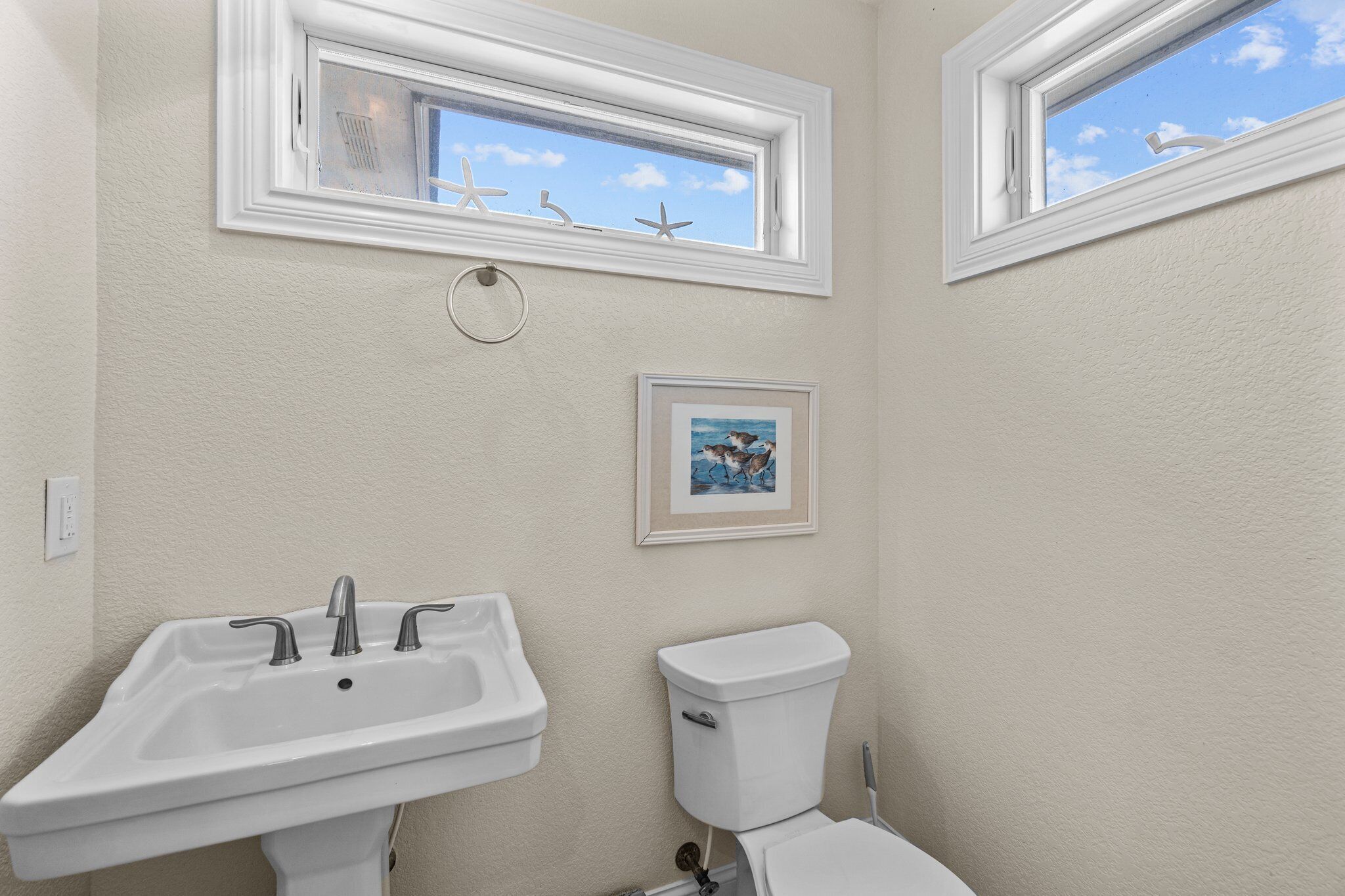A bathroom with a sink, toilet, and a framed picture on the wall.