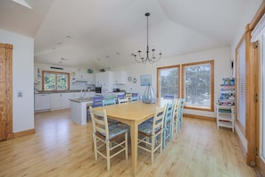 A spacious kitchen with a dining area, wooden flooring, and a chandelier.