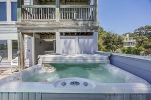A hot tub on a wooden deck with a balcony above.