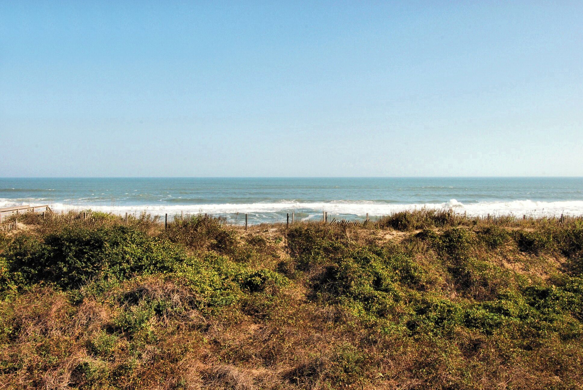 Un paisaje costero con playa, vegetación y cielo despejado.