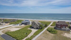 Una propiedad costera con una casa grande, un edificio más pequeño y acceso directo a la playa.