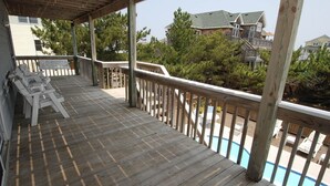 Una terraza de madera con piscina, rodeada de árboles y casas.