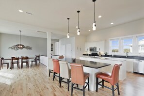 A spacious kitchen with a central island, white cabinetry, and pendant lighting.