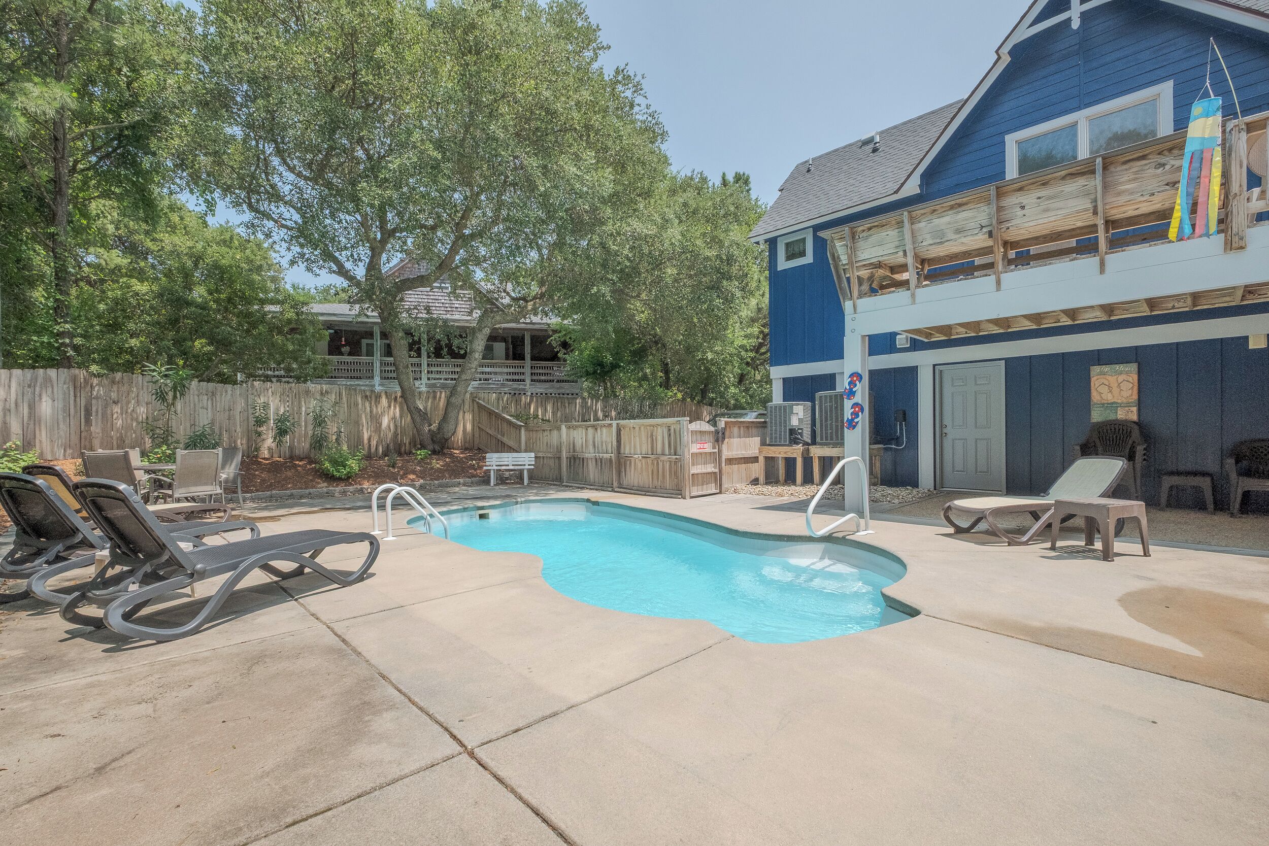 Un jardin avec une piscine, des chaises longues et une terrasse en bois.