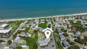 Vista aérea de una zona residencial costera con casas, una playa y un edificio grande con piscina.