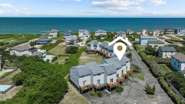Un área residencial costera con casas, una piscina y vistas al mar.