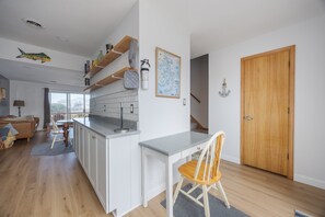 A modern kitchen with white cabinetry, a grey countertop, and a wooden dining table with chairs.