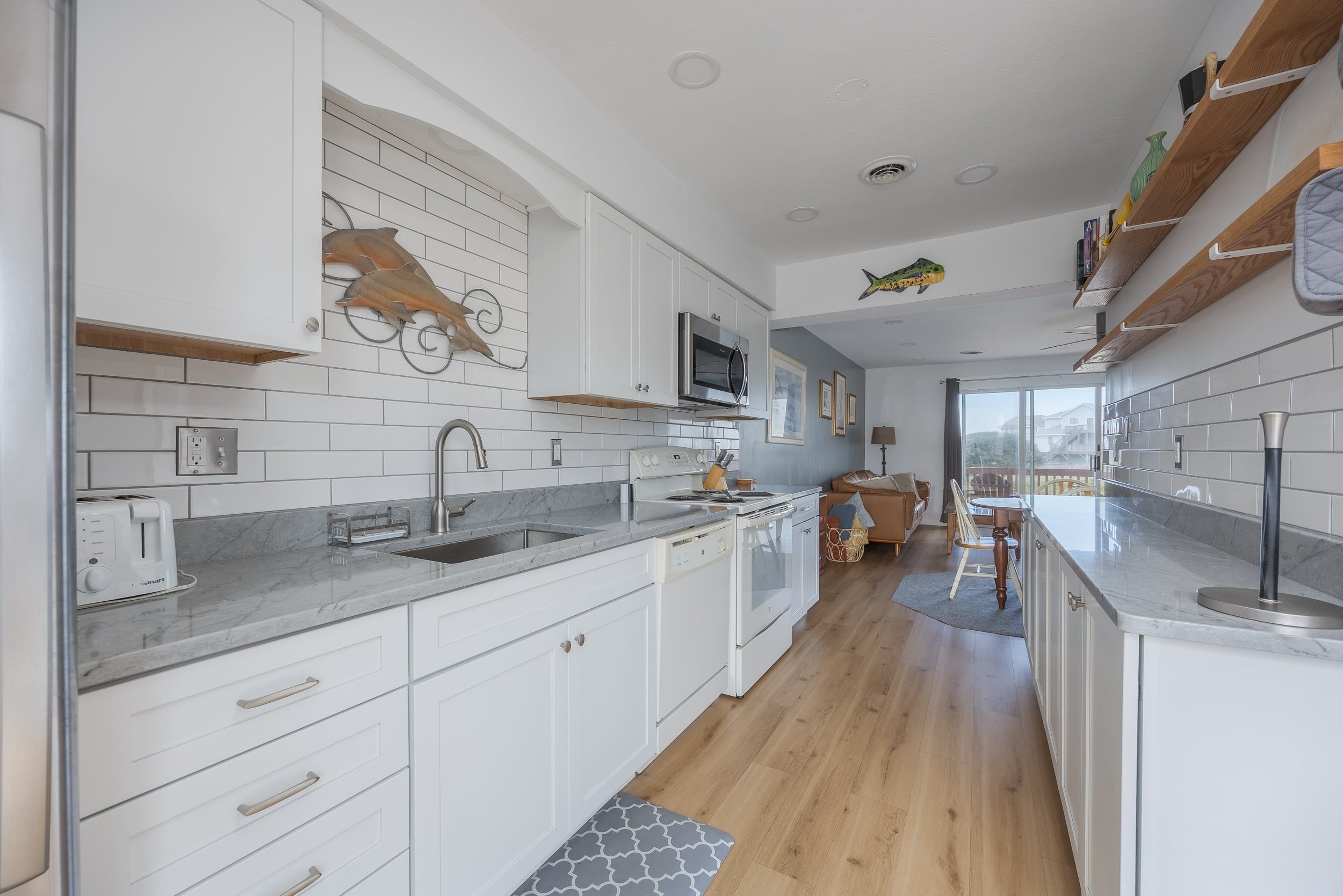A modern kitchen with white cabinetry, a marble countertop, and a built-in oven.