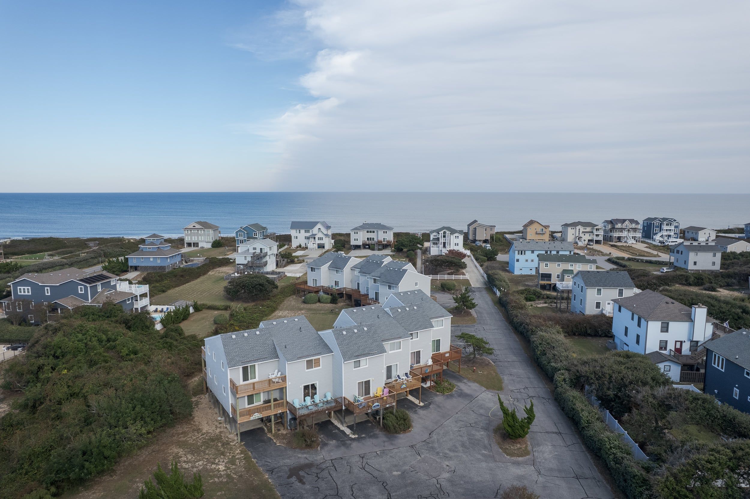 Un quartier résidentiel situé sur la côte, avec des maisons, un ciel dégagé et l’océan en toile de fond.