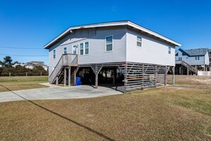 A two-story house with a wooden deck and a staircase leading to the second floor.