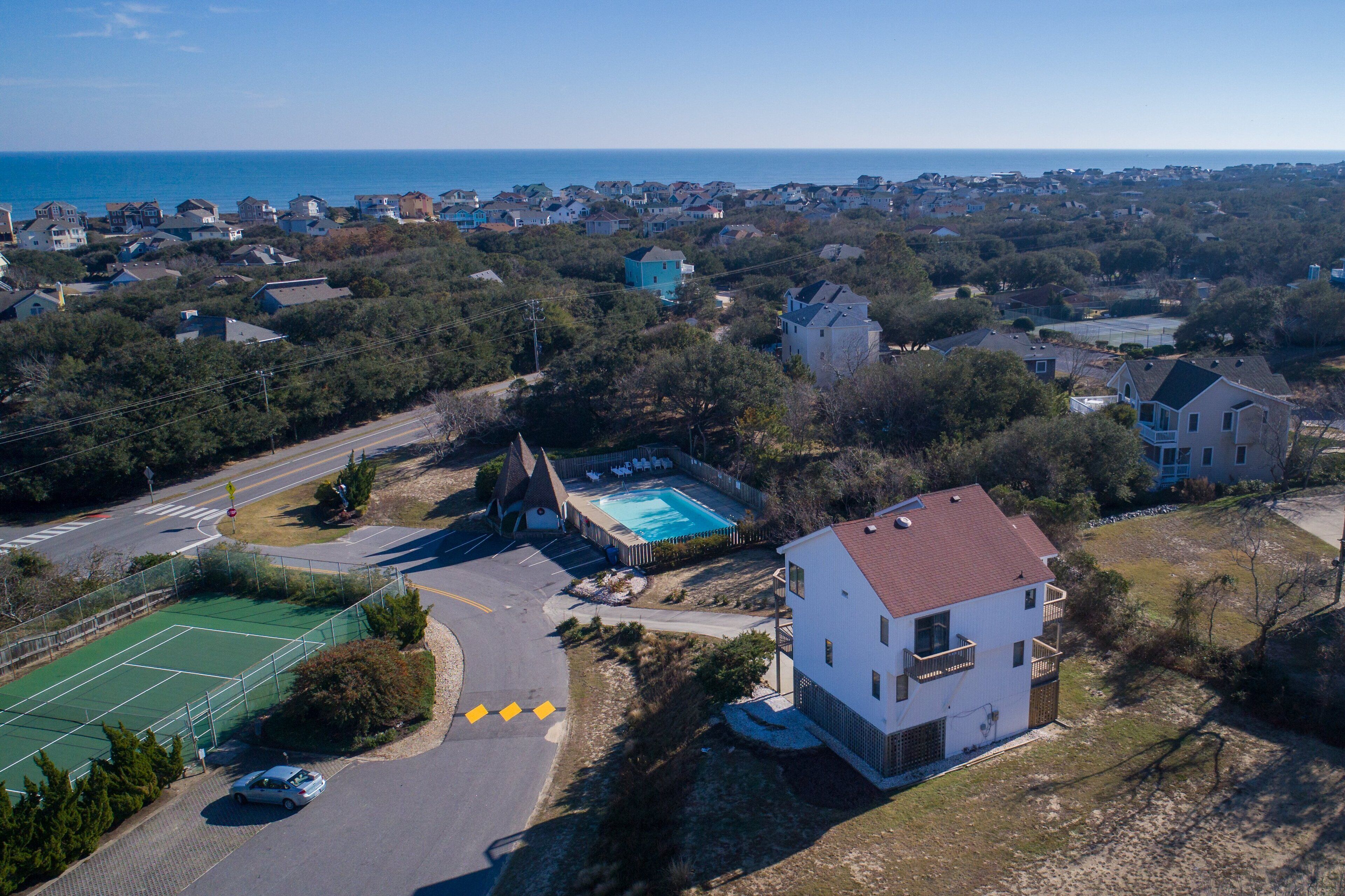 An aerial view of a residential area with houses, a tennis court, and a swimming pool.