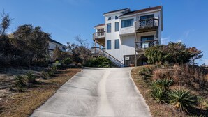 Un immeuble résidentiel à plusieurs étages, doté d’une allée en béton et entouré d’espaces verts aménagés.