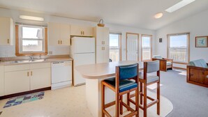 Una cocina moderna con una isla central, sillas de madera y vistas a la ciudad a través de amplios ventanales.