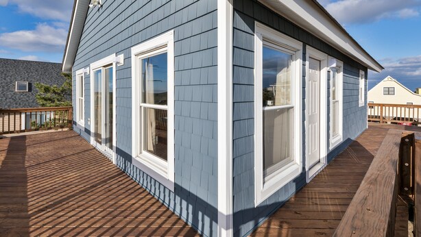 Una casa con fachada azul, detalles blancos y ventanas grandes.