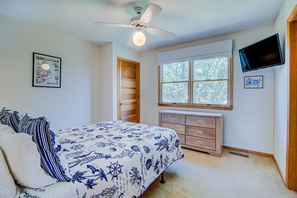 A bedroom with a bed, dresser, ceiling fan, window, and artwork. - 2850 - SunDancer, Pet-Friendly Duck Retreat Near Beach & Town (Duck)