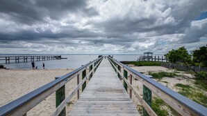 A wooden boardwalk leading to a beach with a pier in the background. - 2850 - SunDancer, Pet-Friendly Duck Retreat Near Beach & Town (Duck)
