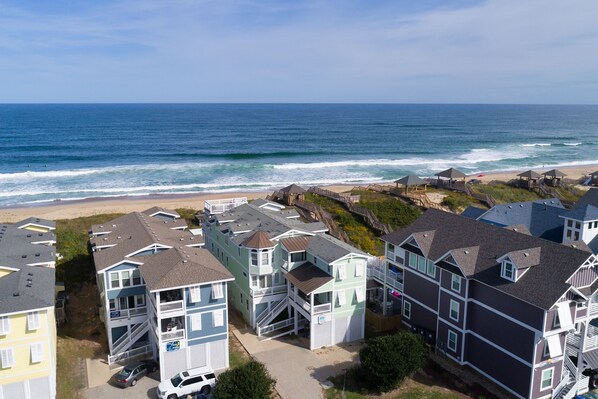 A coastal residential area with multi-story houses, a beach, and a boardwalk.