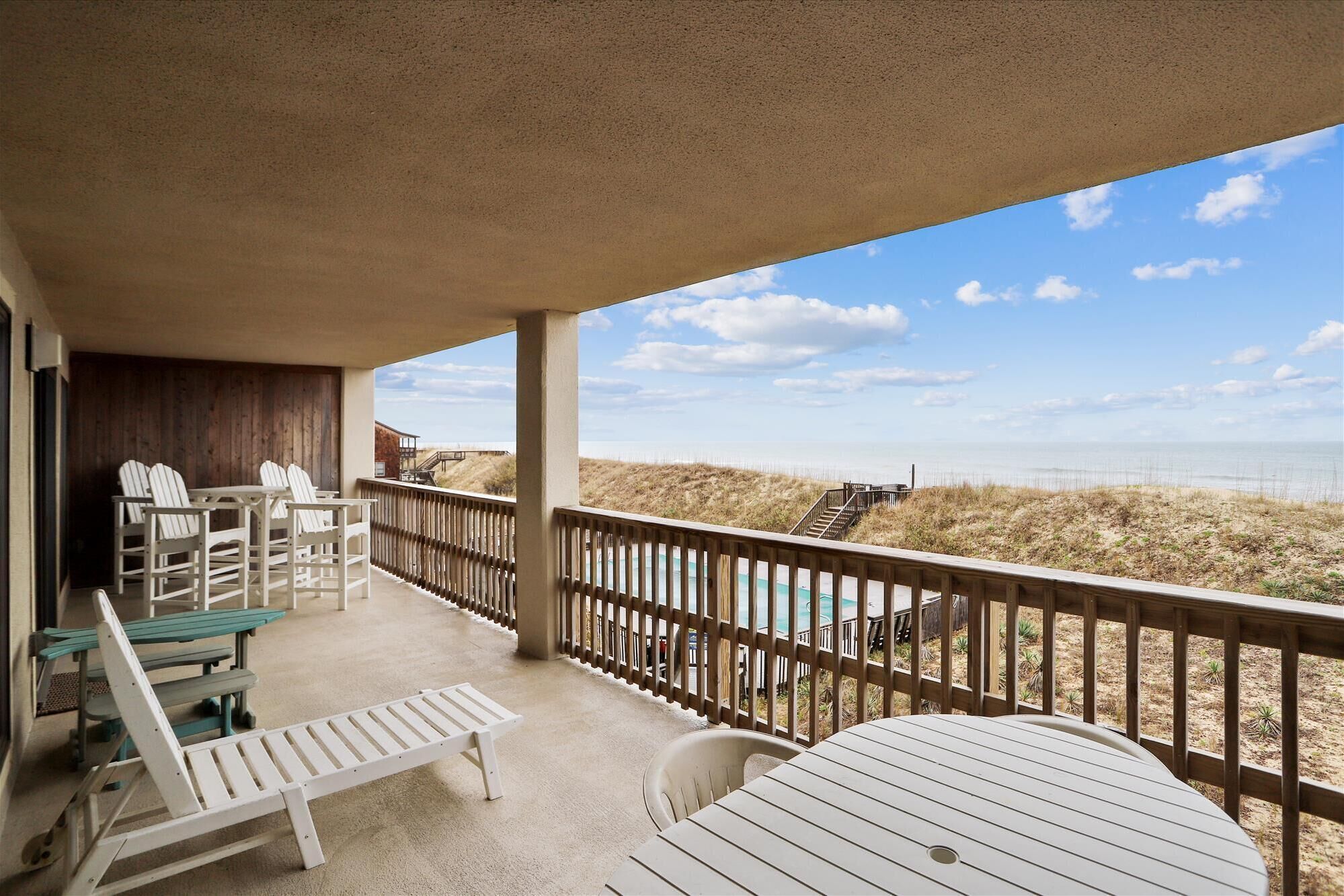 A covered outdoor seating area with a view of the beach and dunes.