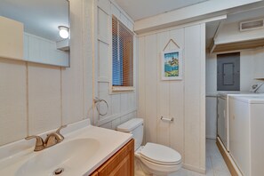 A bathroom with a bathtub, toilet, and a window with blinds.