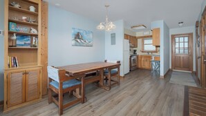 Una cocina amplia con armarios de madera, una mesa de comedor con sillas y una lámpara colgante.