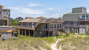 A coastal house with a wooden deck and multiple levels, surrounded by sand dunes and other houses. - 7847- Summerset - Dog Friendly Oceanfront Retreat in Frisco (Frisco)