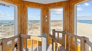 Une chambre d’angle avec des murs en bois et de grandes fenêtres donnant sur la plage.