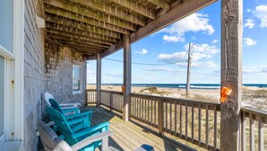 Une terrasse en bois avec des chaises donnant sur une plage.