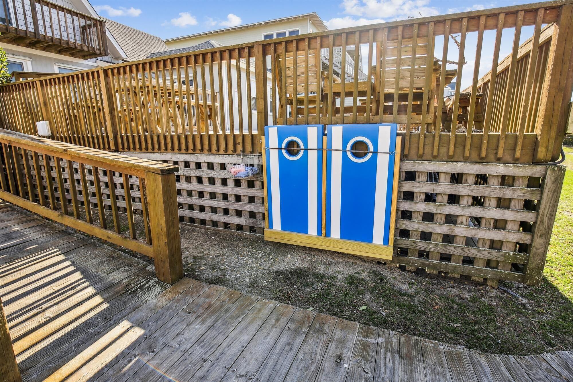 Une terrasse en bois avec un portail en métal, un objet bleu et blanc suspendu au portail, et une clôture en bois en arrière-plan.