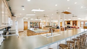 Una cocina amplia con una isla central, taburetes de bar y un comedor con mesa y sillas.
