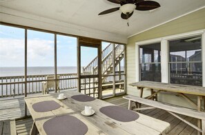 A covered outdoor deck with a wooden table and benches, overlooking the ocean. - 2817 - Aerescape, Soundfront Duck | Hot Tub, Elevator & Sunsets (Duck)