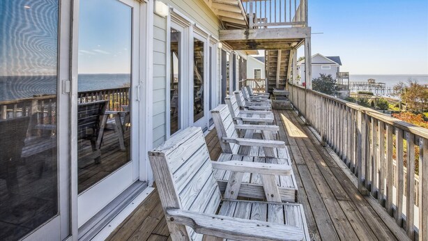 Una terraza de madera con asientos exteriores y vista al océano.