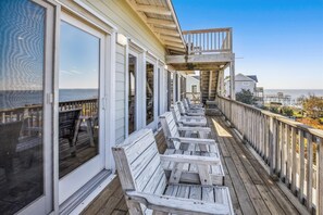 Una terraza de madera con asientos exteriores y vista al océano.